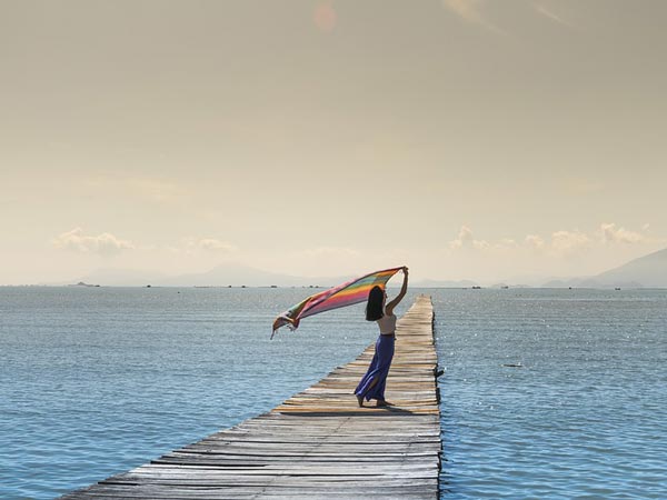 A photo of a woman standing on a long boardwalk found in the middle of the sea