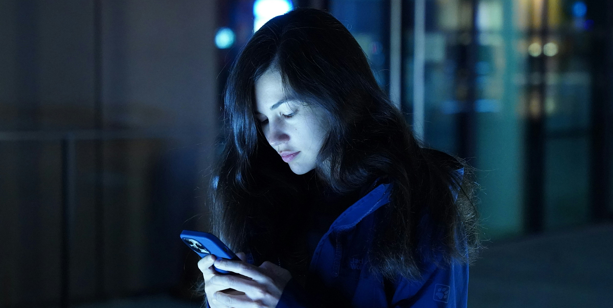 A woman staring at her phone, surrounded by melancholy.